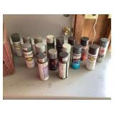Assorted gray and silver spray paint cans in plastic crate